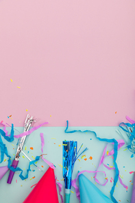Party hat, party blowers and confetti on pink and blue background. happy birthday party celebration fun concept.