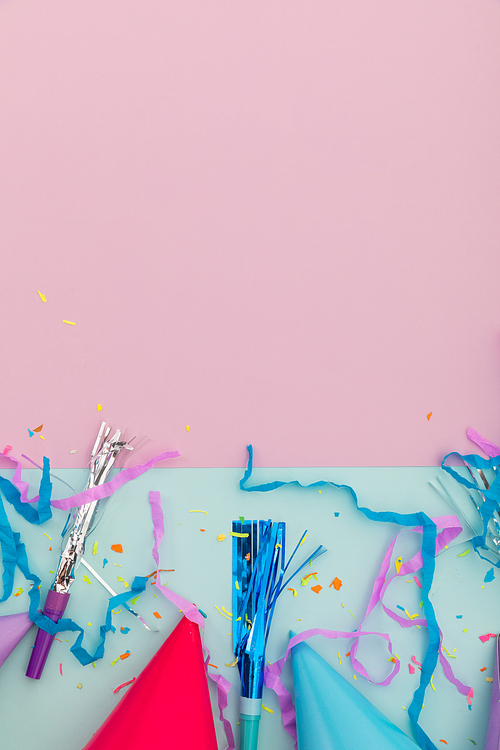 Party hat, party blowers and confetti on pink and blue background. happy birthday party celebration fun concept.