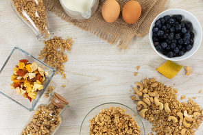 Cereal and blueberries in bowl, cashew nuts, eggs, and milk jug on a wooden table. Food and healthy eating.