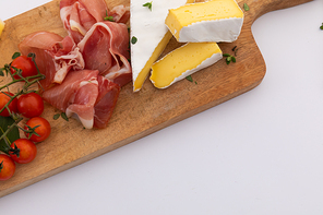 Cheese, ham and cherry tomatoes on wooden board on white background. fresh produce appetizers healthy eating organic food preparation concept.
