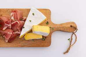 Cheese and ham on wooden board on white background. fresh produce appetizers healthy eating organic food preparation concept.