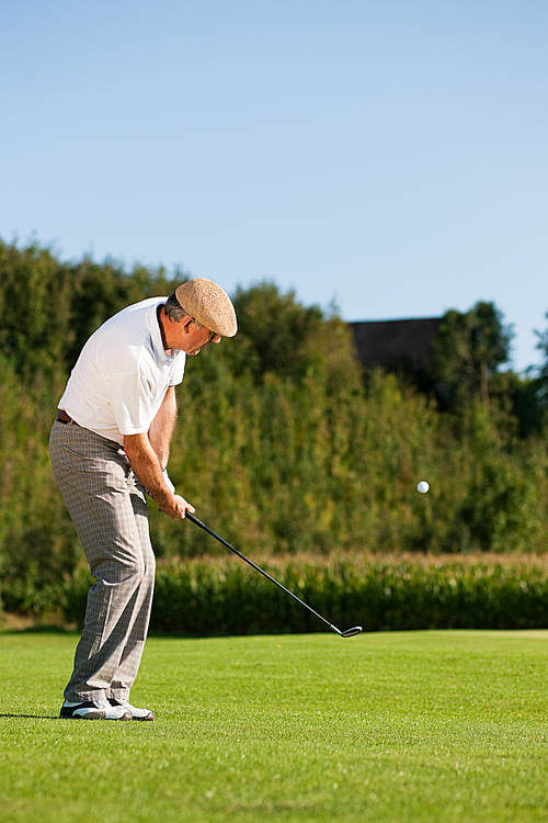 Senior golfer doing a golf stroke|he is playing on a wonderful summer afternoon