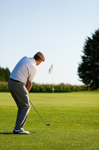 Senior golfer doing a golf stroke|he is playing on a wonderful summer afternoon