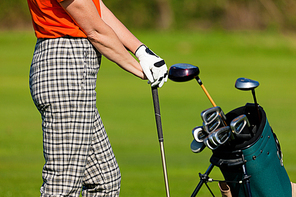 Mature Woman - only torso to be seen - with golf bag playing golf on a golf course