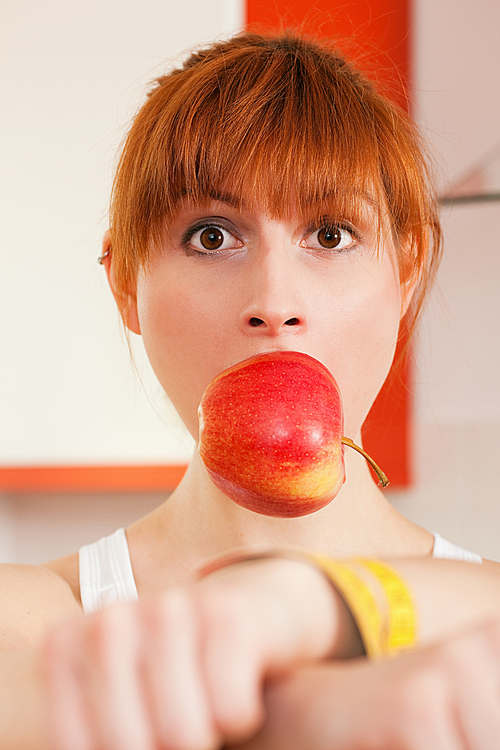 Woman handcuffed by a tape measure and gagged by an apple - symbol for eating disorder