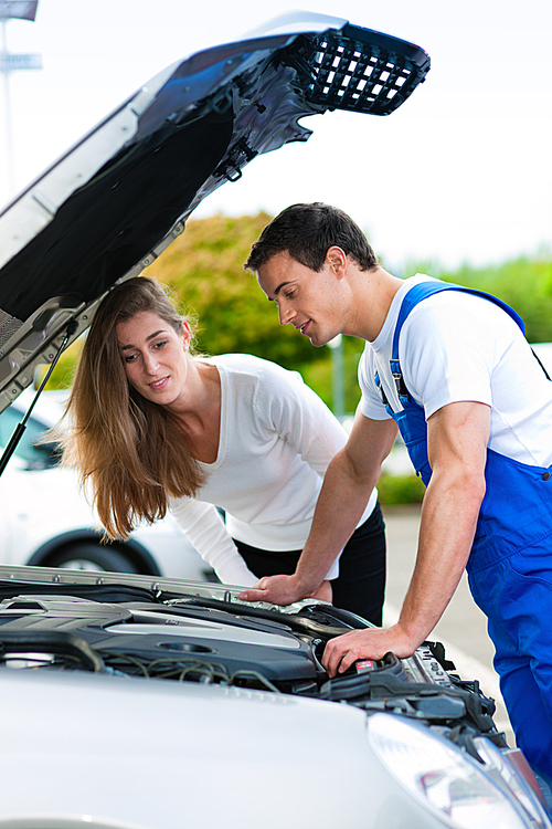 Woman talking to a car mechanic in a parking area|both are standing next to the car