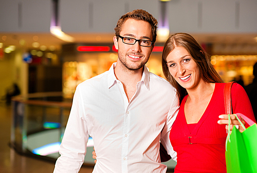 Couple - man and woman - in a shopping mall with colorful bags simply having fun