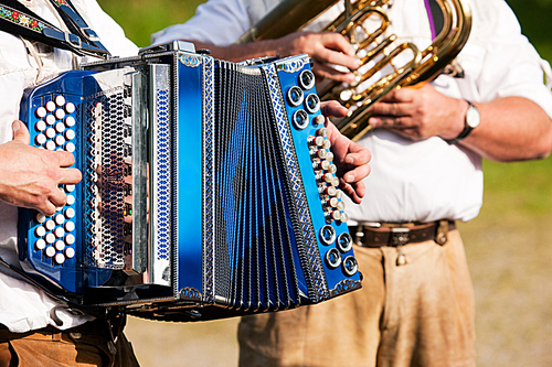 Bavarian traditional band with accordion and tuba playing marching music|only hands of musicians to be seen