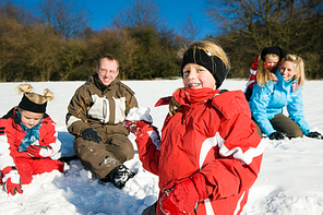 Family with kids having a snowball fight in winter on top of a hill in the snow