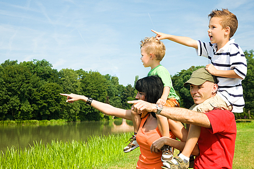 Family carrying their two kids piggyback under a perfect blue sky