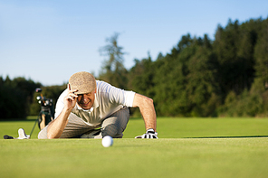 Senior man playing golf aiming for the hole|it is a wonderful clear summer late afternoon|the colors are very vivid