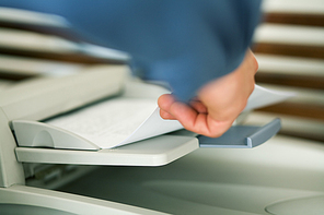 A man (only hand to be seen) faxing documents or taking them out of a printer