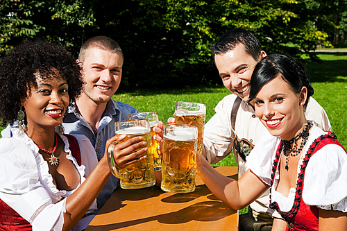 Group of four people - two Couples -  in traditional Bavarian dress|Lederhosen and Dirndl|in a beer garden