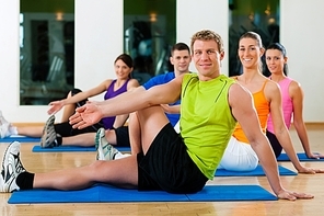 Group of five people is doing stretching exercises in fitness club on gym mats