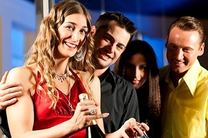 Group of party people with drinks in a bar or club having fun