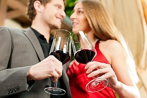 Couple|man and woman|at winetasting in a restaurant|each with glass of red wine in hand