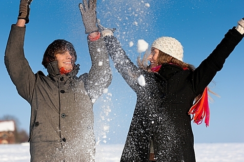 Couple - man and woman - having a winter walk and throwing snow