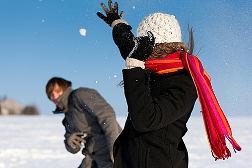 Couple - man and woman - having a winter walk and having a snowball fight