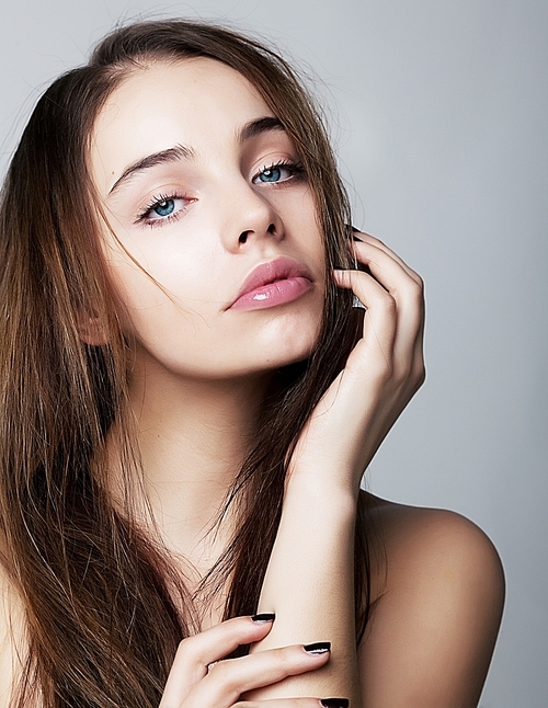 Beautiful young female face with a wellness complexion - isolated on grey