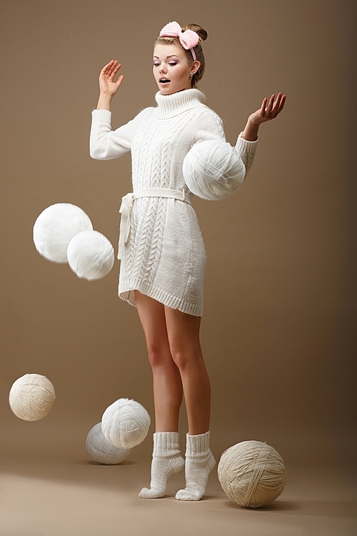 Falling Skeins. Surprised Woman in Woolen Knitted Jersey with White Balls of Yarn
