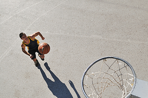 gorup of young boys who playing basketball outdoor on street with long shadows and bird view perspective