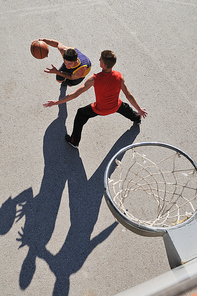 gorup of young boys who playing basketball outdoor on street with long shadows and bird view perspective