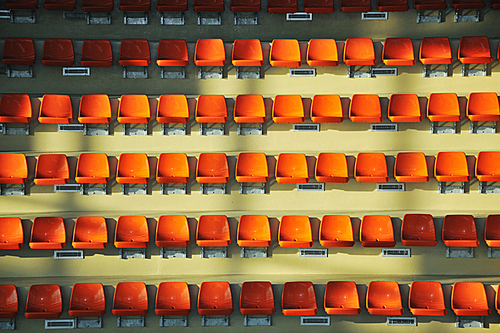 many empty orange seats in sport arena representing audience and crowd concept