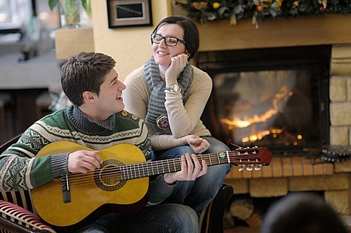 happy Young romantic couple sitting on sofa in front of fireplace at winter season in home