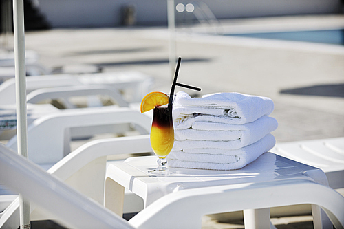 coctail dring with orange att sunny day on swimming pool side with white towel decoraton