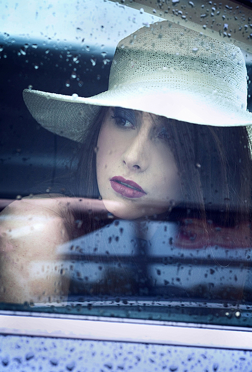 Young attractive woman looking through window after rain