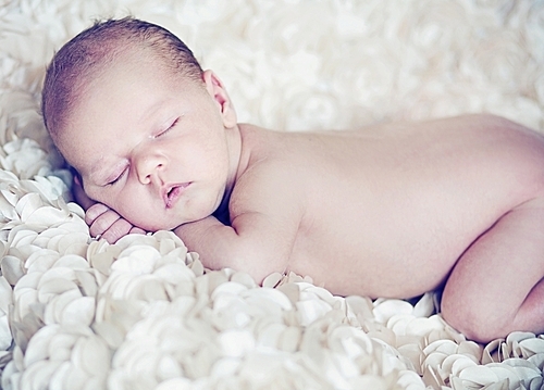Cute baby sleeping on soft white petals