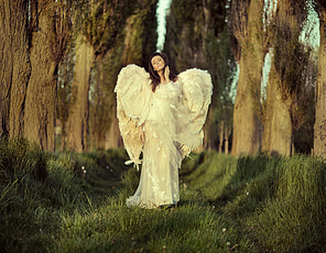 Wonderful female angel walking across the spring forest