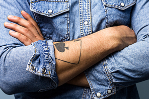 Young man with tattoo is crossing his arms