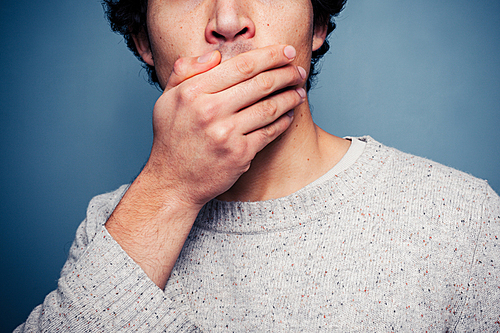Young man covering his mouth