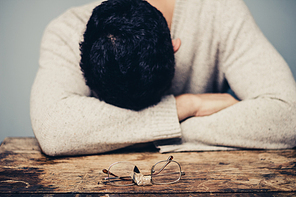 Tired man at desk with broken glasses