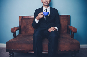 Young businessman drinking coffee on a sofa