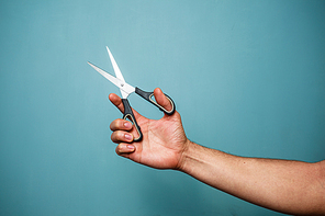 Man’s hand is holding a pair of open scissors