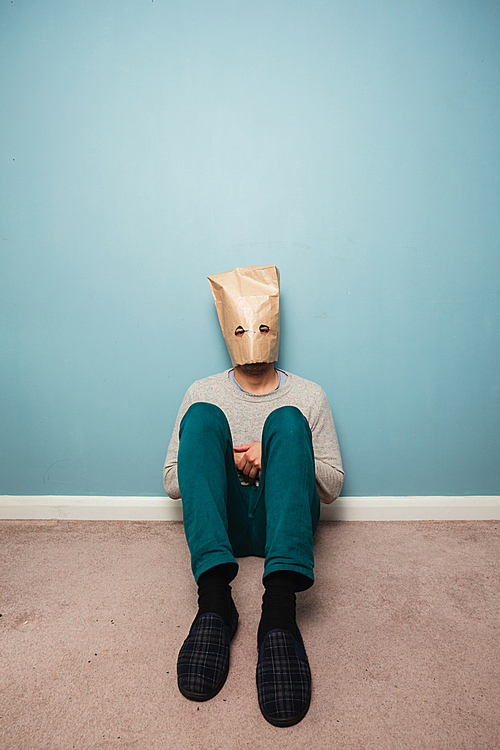 Man with a bag over his head is sitting on the floor