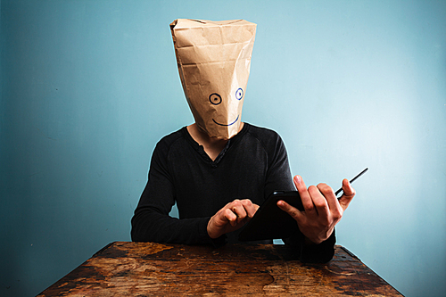 Man with bag over head using tablet