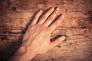 A man is resting his left hand on a table
