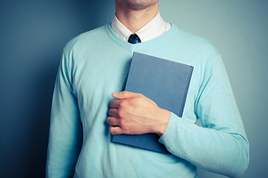 A young man is holding a big blue book