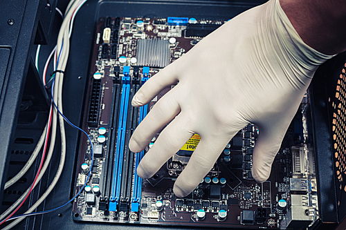 A hand wearing a rubber glove is installing computer components