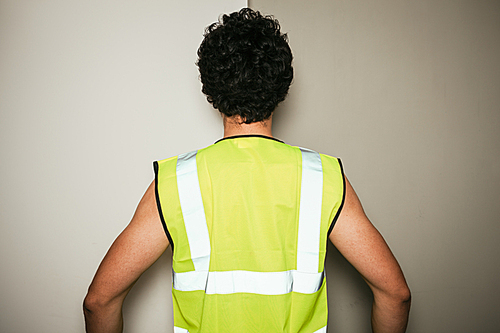 Rear view of a builder in a high visibility vest against a green and white background