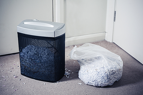 A paper shredder and a bag of shredded documents by the door