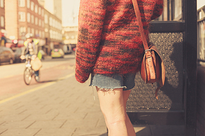 A young woman is waiting at the bus stop on a sunny day