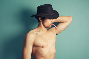 a  shirtless young cowboy is smoking a cigarette