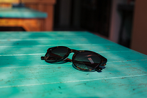 A pair of sunglasses on a blue table in the sunlight