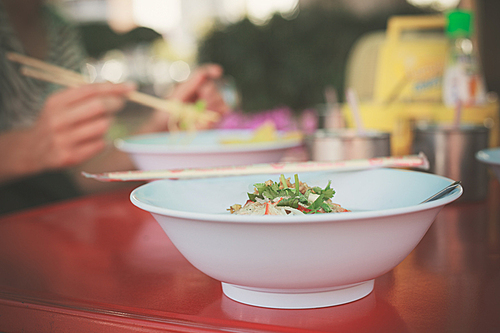 Bowl of noodles outside by the street with a woman in the background