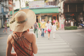 A young woman is walking on the street of an asian country on a sunny day