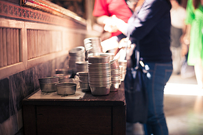 Pans with coins in Asian temple with people in the background